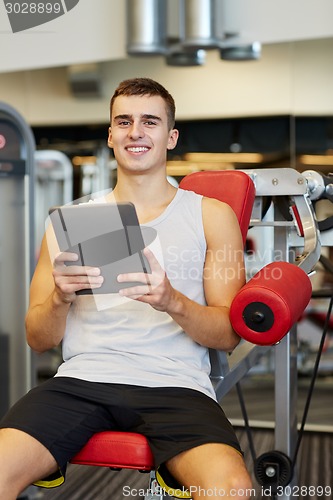 Image of smiling young man with tablet pc computer in gym