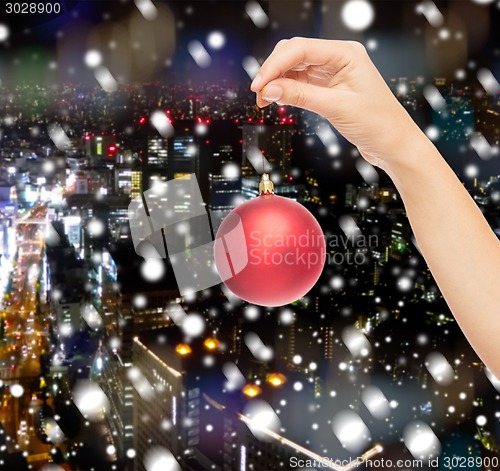 Image of close up of woman in sweater with christmas ball