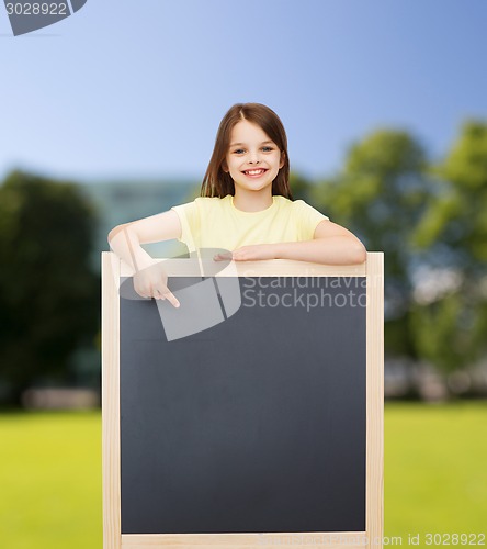 Image of happy little girl pointing finger to blackboard