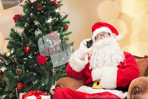 Image of santa claus with smartphone and christmas tree