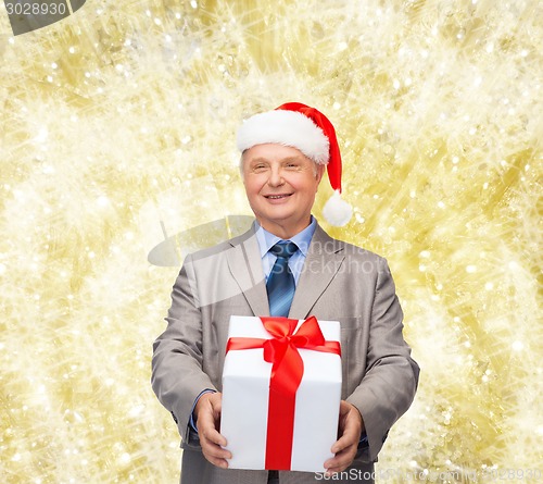 Image of smiling man in suit and santa helper hat with gift