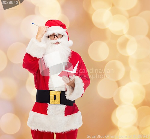 Image of man in costume of santa claus with notepad