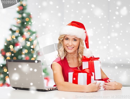 Image of woman with gift boxes and laptop computer