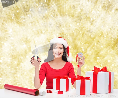 Image of smiling woman in santa helper hat packing gifts