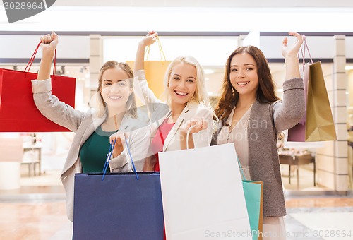 Image of happy young women with shopping bags in mall