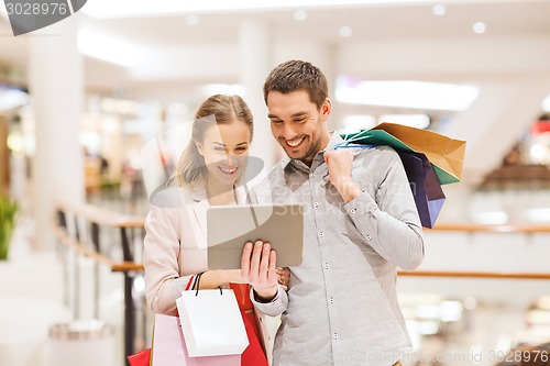 Image of couple with tablet pc and shopping bags in mall