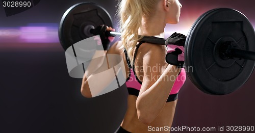 Image of sporty woman exercising with barbell from back