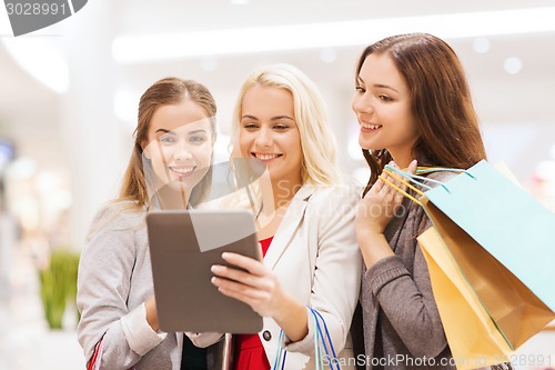 Image of happy young women with tablet pc and shopping bags