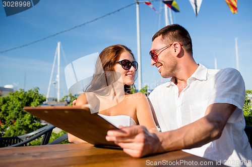 Image of smiling couple with menu at cafe