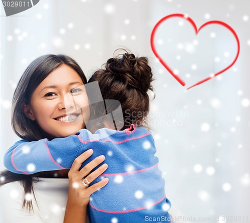 Image of smiling little girl and mother hugging indoors