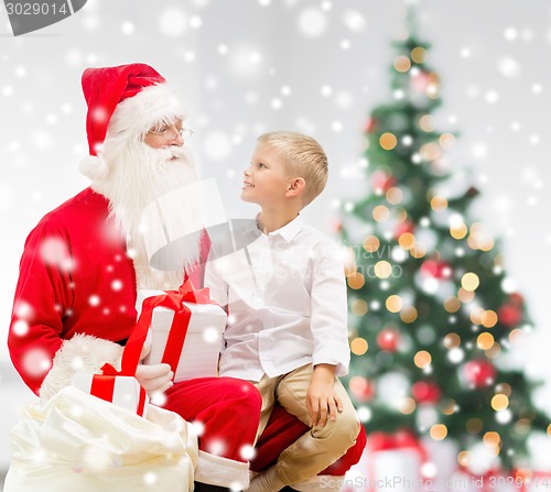 Image of smiling little boy with santa claus and gifts