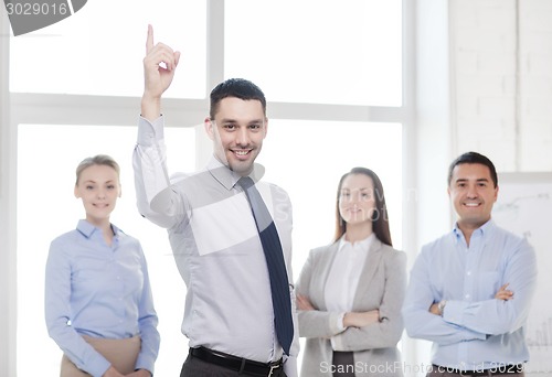 Image of smiling businessman in office with team on back