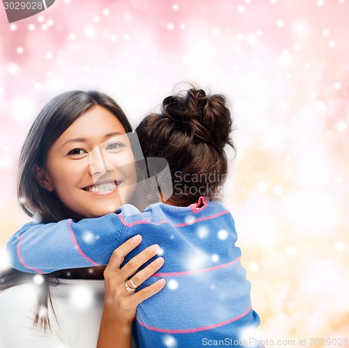 Image of smiling little girl and mother hugging indoors