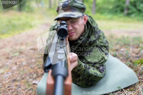 Image of close up of soldier or hunter with gun in forest