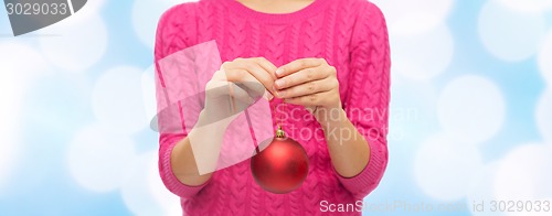 Image of close up of woman in sweater with christmas ball