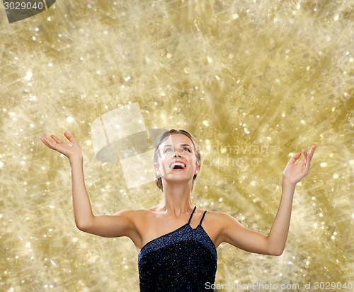 Image of smiling woman raising hands and looking up