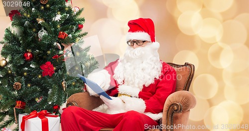 Image of man in costume of santa claus with tablet pc