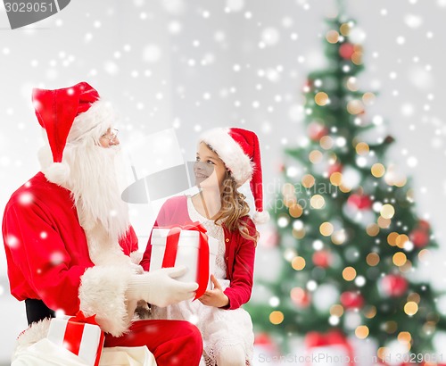 Image of smiling little girl with santa claus and gifts