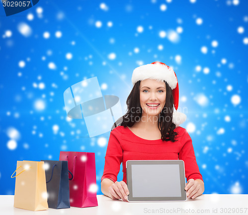 Image of smiling woman with shopping bags and tablet pc