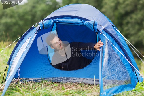 Image of smiling male tourist with beard in tent