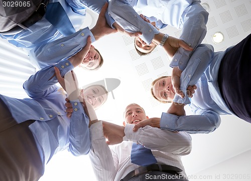 Image of smiling group of businesspeople standing in circle