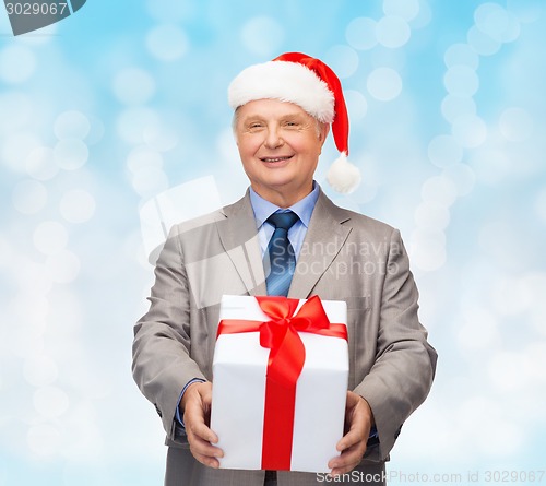 Image of smiling man in suit and santa helper hat with gift