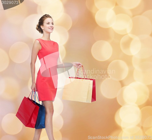Image of smiling elegant woman in dress with shopping bags