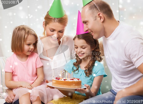 Image of happy family with two kids in party hats at home