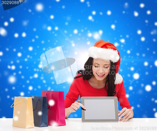 Image of smiling woman with shopping bags and tablet pc