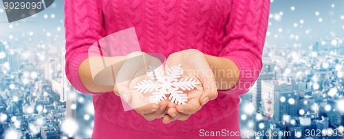 Image of close up of woman in sweater holding snowflake