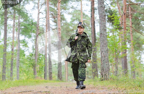 Image of young soldier or hunter with gun in forest