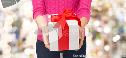 Image of close up of woman in pink sweater holding gift box