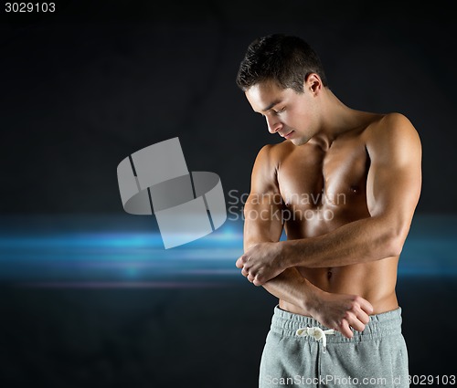 Image of young male bodybuilder injured touching elbow