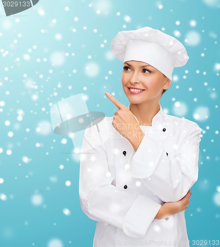 Image of smiling female chef dreaming pointing finger up