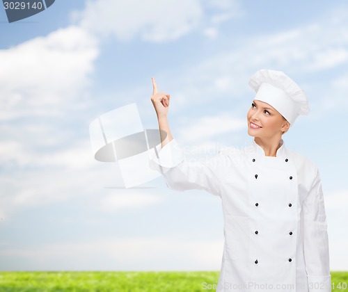 Image of smiling female chef pointing finger to something