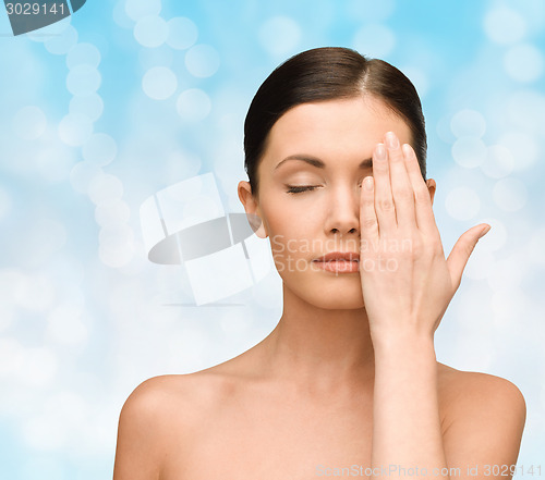 Image of smiling young woman covering face with hand