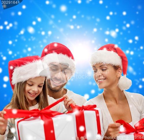 Image of happy family in santa helper hats with gift boxes