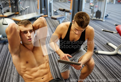 Image of men flexing abdominal muscles in gym