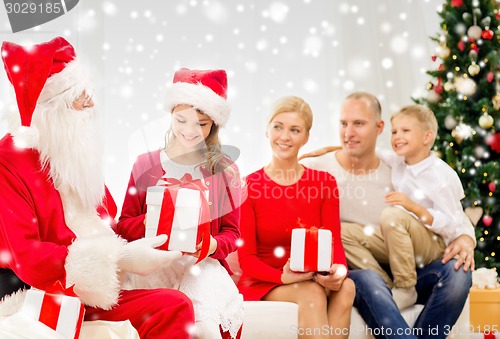 Image of smiling family with santa claus and gifts at home