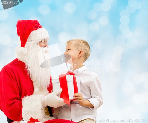 Image of smiling little boy with santa claus and gifts