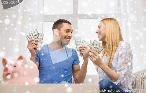 Image of happy couple with money and piggybank at home