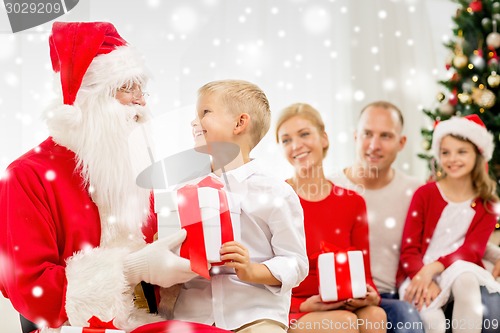 Image of smiling family with santa claus and gifts at home