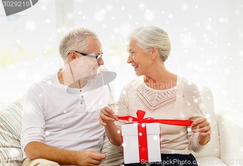 Image of happy senior couple with gift box at home