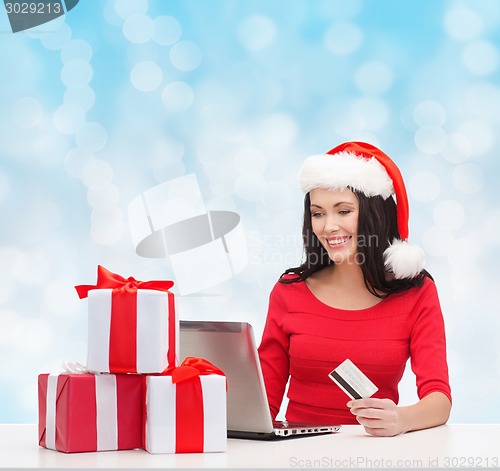 Image of smiling woman with gifts, laptop and credit card