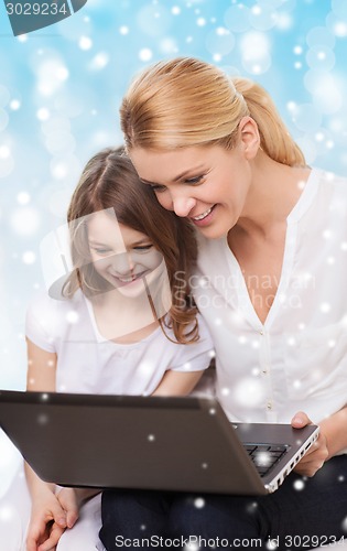 Image of smiling mother and little girl with laptop