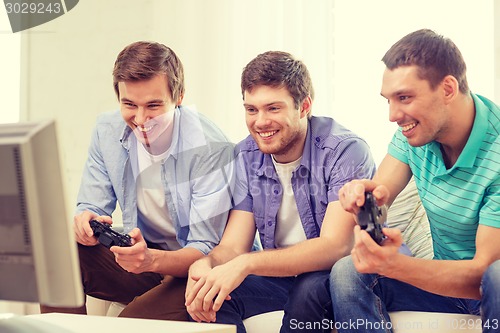 Image of smiling friends playing video games at home