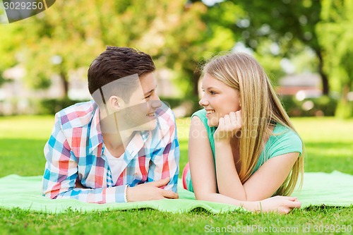 Image of smiling couple lying on blanket in park