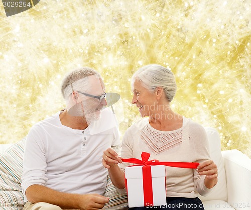 Image of happy senior couple with gift box at home