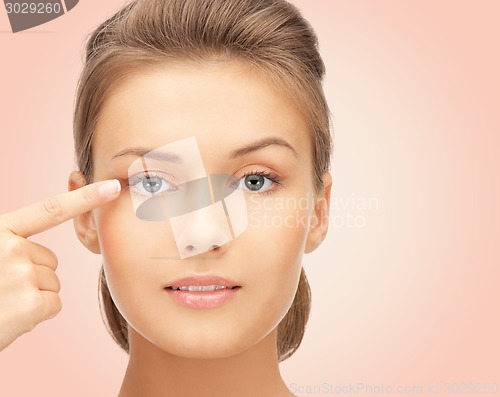 Image of beautiful young woman pointing finger to her eye