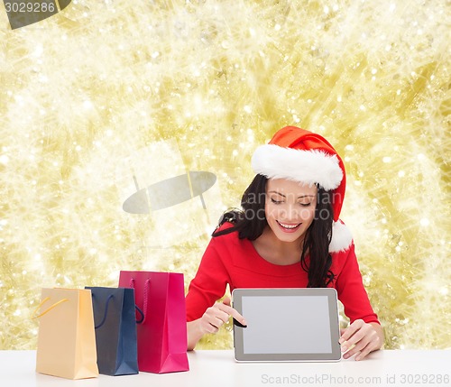 Image of smiling woman with shopping bags and tablet pc